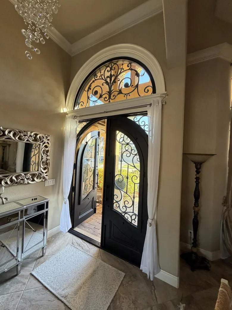 Completed grand arched iron entrance — final walkthrough with door open showing quality details