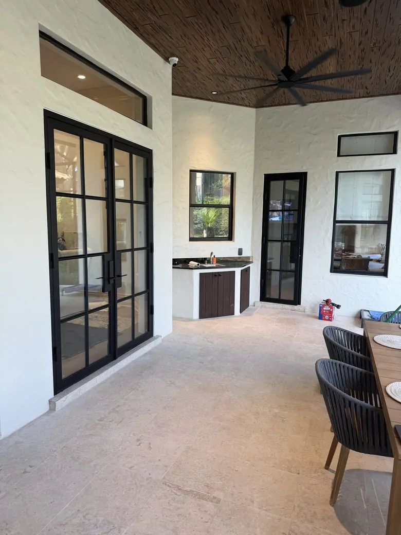 Covered loggia with matching black steel-and-glass doors and windows and an outdoor living area