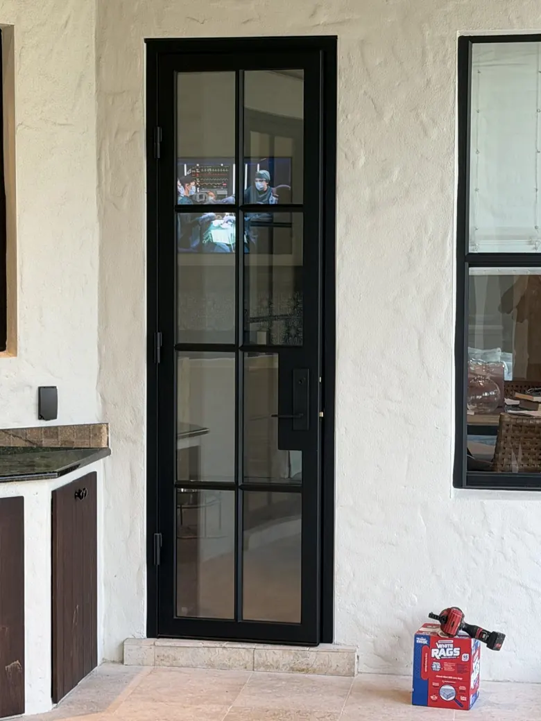 Narrow black steel-and-glass door with divided lites beside an outdoor kitchen